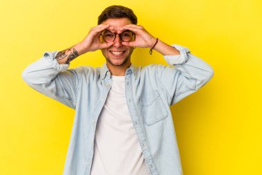 Sarı arka planda izole edilmiş dövmeleri olan beyaz bir adam gözlerinde sorun olmadığını gösteriyor.