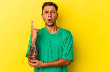 Sarı arka planda izole edilmiş dövmeleri olan beyaz bir genç adam. Harika bir fikri var, yaratıcılık kavramı..