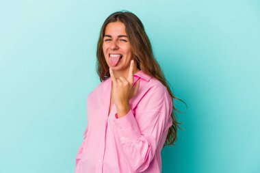 Mavi arka planda izole edilmiş genç beyaz kadın parmaklarıyla taş hareketi gösteriyor.