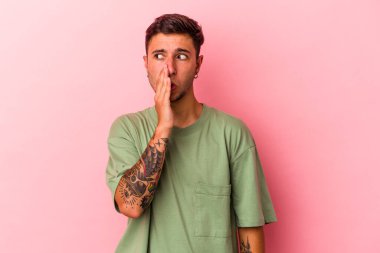 Sarı arka planda izole edilmiş dövmeleri olan beyaz genç bir adam gizli bir fren haberinin olduğunu söylüyor.