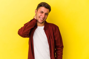 Sarı arka planda izole edilmiş beyaz dövmeli genç bir adam sabit yaşam tarzından dolayı boyun ağrısı çekiyor..