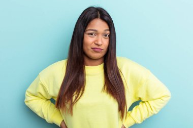 Genç Venezuelalı bir kadın mavi arka planda soyutlanmış üzgün, ciddi bir yüz, mutsuz ve hoşnutsuz.