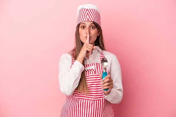 ピンクの背景に隔離されたスプーンを保持している若いアイスクリームメーカーの女性秘密を維持するか 沈黙を求めて — ストック写真