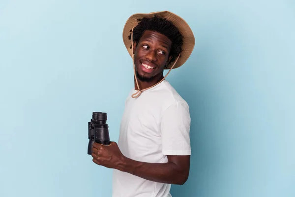 Молодий Афроамериканець Тримає Бінокль Ізольованим Синьому Фоні Дивиться Убік Усміхаючись — стокове фото