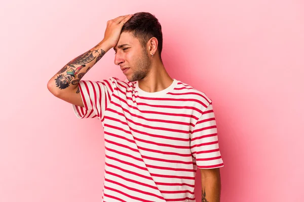 Sarı arka planda izole edilmiş dövmeleri olan genç beyaz bir adam bir şeyi unutuyor. Alnına avuç içi ve kapalı gözlerle tokat atıyor..