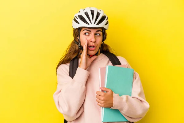 若いです白人学生女性身に着けています自転車ヘルメット黄色の背景に隔離されていますと言っています秘密のホットブレーキニュースと脇を見て — ストック写真