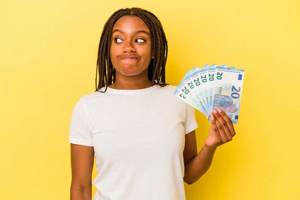 Mladá Afroameričanka Držící Bankovky Izolované Žlutém Pozadí Zmatená Nedůvěřivá Nejistá — Stock fotografie