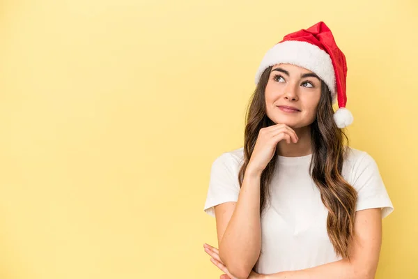 若いですCaucasian女性祝いますクリスマス孤立した上に黄色の背景見て横に疑いと懐疑的な表現 — ストック写真