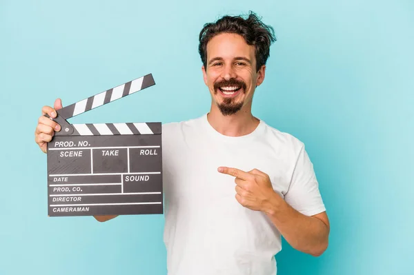 Young Caucasian Man Holding Clapperboard Isolated Blue Background Smiling Pointing — Stock Photo, Image