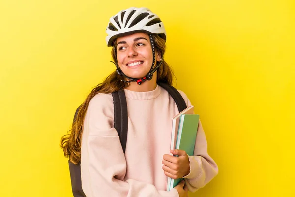 黄色の背景に隔離された自転車のヘルメットを身に着けている若い白人学生の女性は笑顔 陽気で楽しい脇に見えます — ストック写真