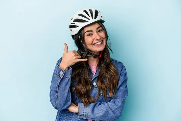 Young caucasian woman rinding a bike isolated on blue background showing a mobile phone call gesture with fingers.