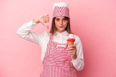 Elinde dondurma tutan genç bir kadın pembe arka planda izole edilmiş, hoşlanmadığı bir jest gösteriyor, başparmakları aşağıda. Anlaşmazlık konsepti.