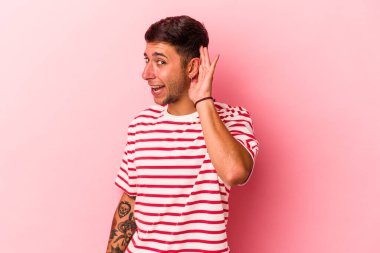 Sarı arka planda izole edilmiş dövmeleri olan beyaz bir adam bir dedikoduyu dinlemeye çalışıyor..