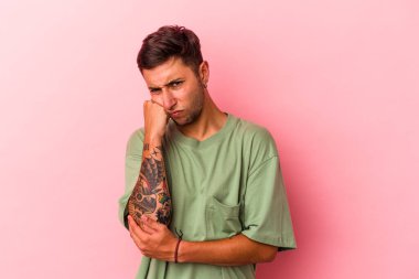 Sarı arka planda izole edilmiş dövmeleri olan, üzgün ve dalgın hisseden, kopyalama alanına bakan genç beyaz bir adam..