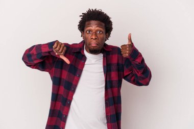 Beyaz arka planda izole edilmiş genç Afro-Amerikalı adam baş parmağını kaldırıyor ve baş parmağını aşağı gösteriyor, zor seçim konsepti