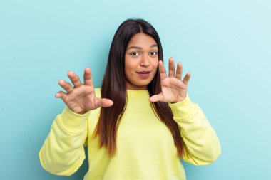 Genç Venezuelalı bir kadın mavi arka planda izole edildi.