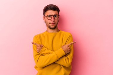 Sarı arka plan noktalarında izole edilmiş dövmeleri olan beyaz genç bir adam iki seçenek arasında seçim yapmaya çalışıyor..