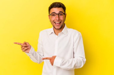 Sarı arka planda izole edilmiş beyaz dövmeli genç bir adam işaret parmağıyla işaret ederek heyecanlanıyor..