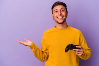 Mor arka planda, elinde oyun kumandası olan genç beyaz bir adam bir avuç içinde fotokopi alanı ve belinde başka bir el tutuyor..