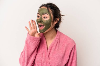 Young caucasian woman wearing a facial mask isolated on white background shouting and holding palm near opened mouth.