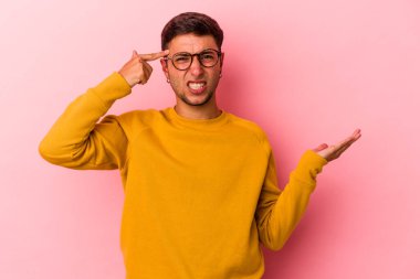 Sarı arka planda izole edilmiş dövmeleri olan genç beyaz bir adam elinde bir ürün taşıyor..