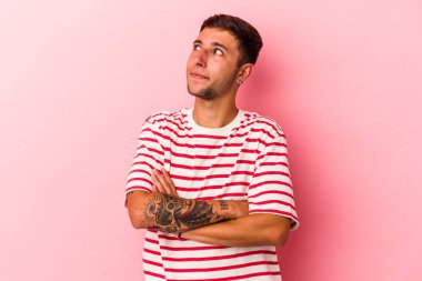 Sarı arka planda izole edilmiş dövmeleri olan genç beyaz adam amaçlarına ve amaçlarına ulaşmayı hayal ediyor.