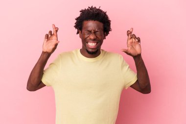 Genç Afrikalı Amerikalı adam pembe arka planda izole edilmiş şans diliyor.