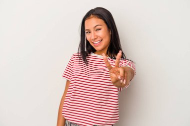 Beyaz arka planda izole edilmiş genç Latin kadın zafer işareti gösteriyor ve gülümsüyor..