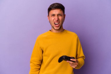 Mor arka planda izole edilmiş oyun kontrolörünü tutan genç beyaz adam çok sinirli ve agresif çığlıklar atıyor..