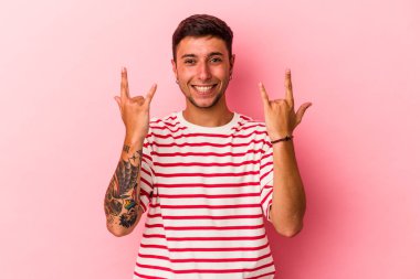 Sarı arka planda izole edilmiş dövmeleri olan genç beyaz bir adam boynuzlarını devrim konsepti olarak gösteriyor..