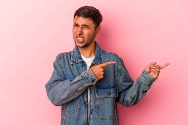 Sarı arka planda izole edilmiş beyaz dövmeli genç bir adam işaret parmağıyla fotokopi alanını işaret ederek heyecan ve arzusunu ifade ediyor..