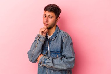 Sarı arka planda izole edilmiş, şüpheli ve şüpheci bir ifadeyle yan bakan beyaz dövmeli genç bir adam..