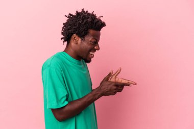 Genç Afrikalı Amerikalı adam pembe arka planda izole edilmiş, başparmak uzakta, gülüyor ve kaygısız..