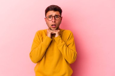 Sarı arka planda izole edilmiş beyaz dövmeli genç bir adam şans için dua ediyor, şaşırıyor ve ağzını açıyor..