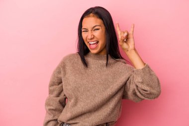 Pembe arka planda izole edilmiş genç Latin kadın boynuzlarını devrim konsepti olarak gösteriyor..