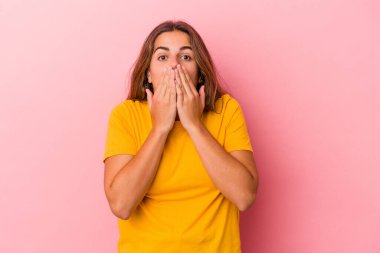 Pembe arka planda izole edilmiş beyaz bir kadın elleriyle ağzını kapatırken şok oldu..