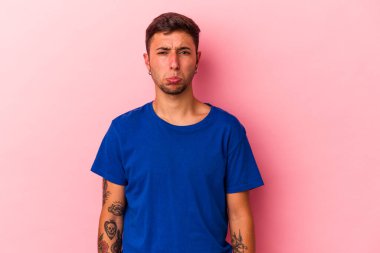 Sarı arka planda izole edilmiş beyaz dövmeli genç bir adam üzgün, ciddi yüzlü, mutsuz ve hoşnutsuz..