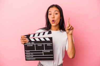 Pembe arka planda el çırpma tahtası tutan genç Latin kadının harika bir fikri var, yaratıcılık kavramı..