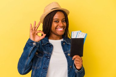 Pasaportu olan Afrikalı genç bir Amerikalı kadın sarı arka planda izole edilmiş neşeli ve kendinden emin..