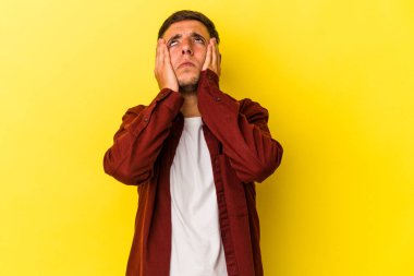 Sarı arka planda izole edilmiş, ağlayan ve sızlanan, dövmeleri olan beyaz bir genç..