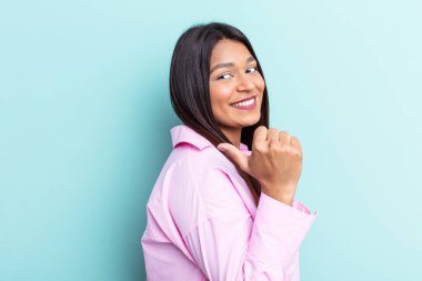 Genç Venezuelalı kadın mavi arka plan noktalarında izole edilmiş başparmak uzakta, gülüyor ve kaygısız.