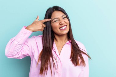 Genç Venezuelalı bir kadın mavi arka planda izole edilmiş işaret parmağıyla hayal kırıklığı jesti yapıyor..