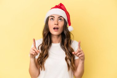Sarı arka planda izole edilmiş, ağzı açık genç beyaz kadın Noel 'i kutluyor..