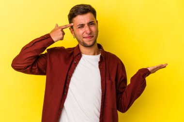 Sarı arka planda dövmeleri olan beyaz genç bir adam işaret parmağıyla yaptığı hayal kırıklığını gösteriyor..