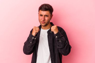 Sarı arka planda izole edilmiş dövmeleri olan genç beyaz bir adam kameraya yumruk gösteriyor, agresif bir yüz ifadesi var..