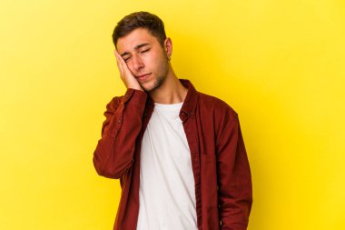 Sarı arka planda dövmeleri olan, sıkılmış, yorgun ve dinlenmeye ihtiyacı olan beyaz bir genç adam..