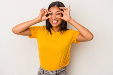 Beyaz arka planda izole edilmiş genç Latin bir kadın bir başarı fırsatı bulmak için gözlerini açık tutuyor..