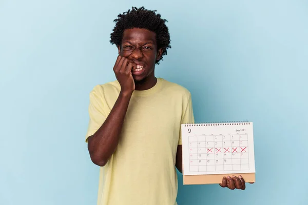 Mladý Africký Američan Drží Kalendář Izolované Modrém Pozadí Kousání Nehty — Stock fotografie