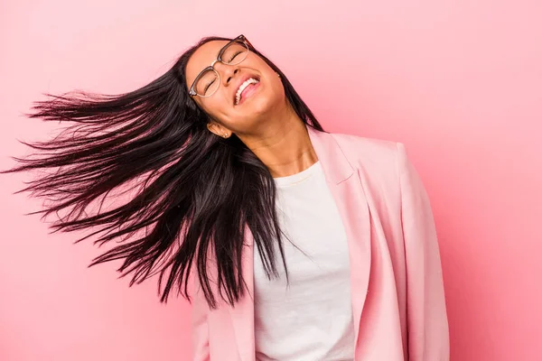 Pembe arka planda izole edilmiş genç Latin kadın dans ediyor ve eğleniyor..