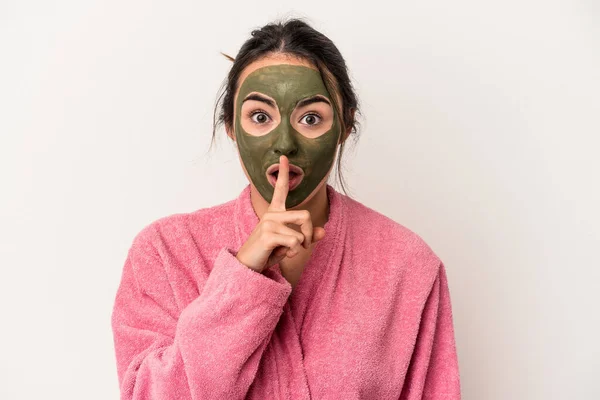 Young caucasian woman wearing a facial mask isolated on white background keeping a secret or asking for silence.